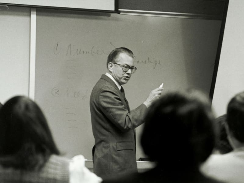 Dr. Zuck looking at students while writing on a whiteboard in a DTS classroom